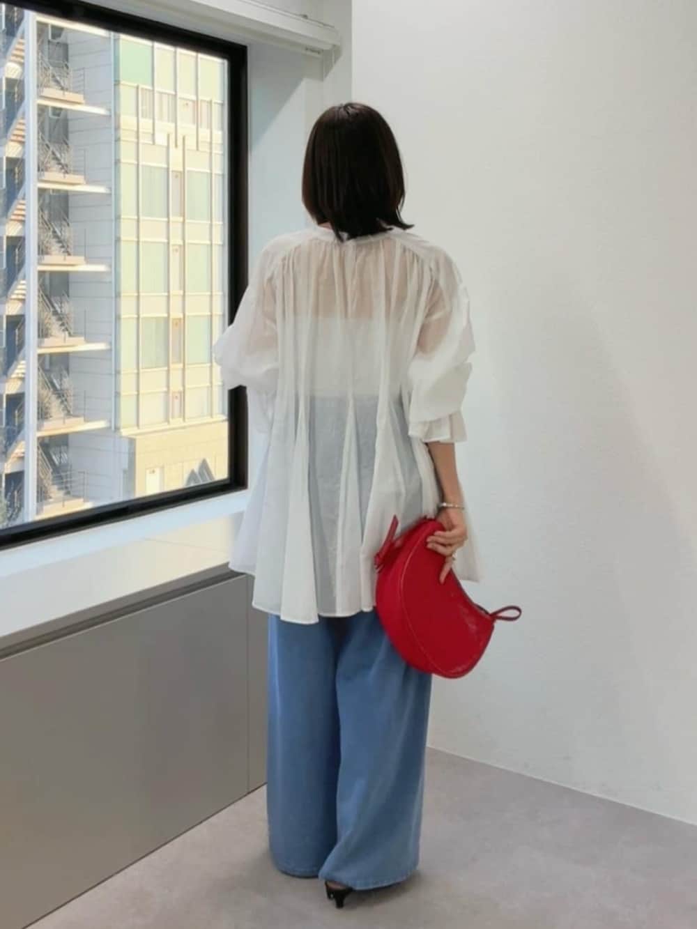 ブラック系のサンダル、ブルー系のデニムパンツ、レッド系のハンドバッグを着用したレディースの春コーディネートの3枚目の写真