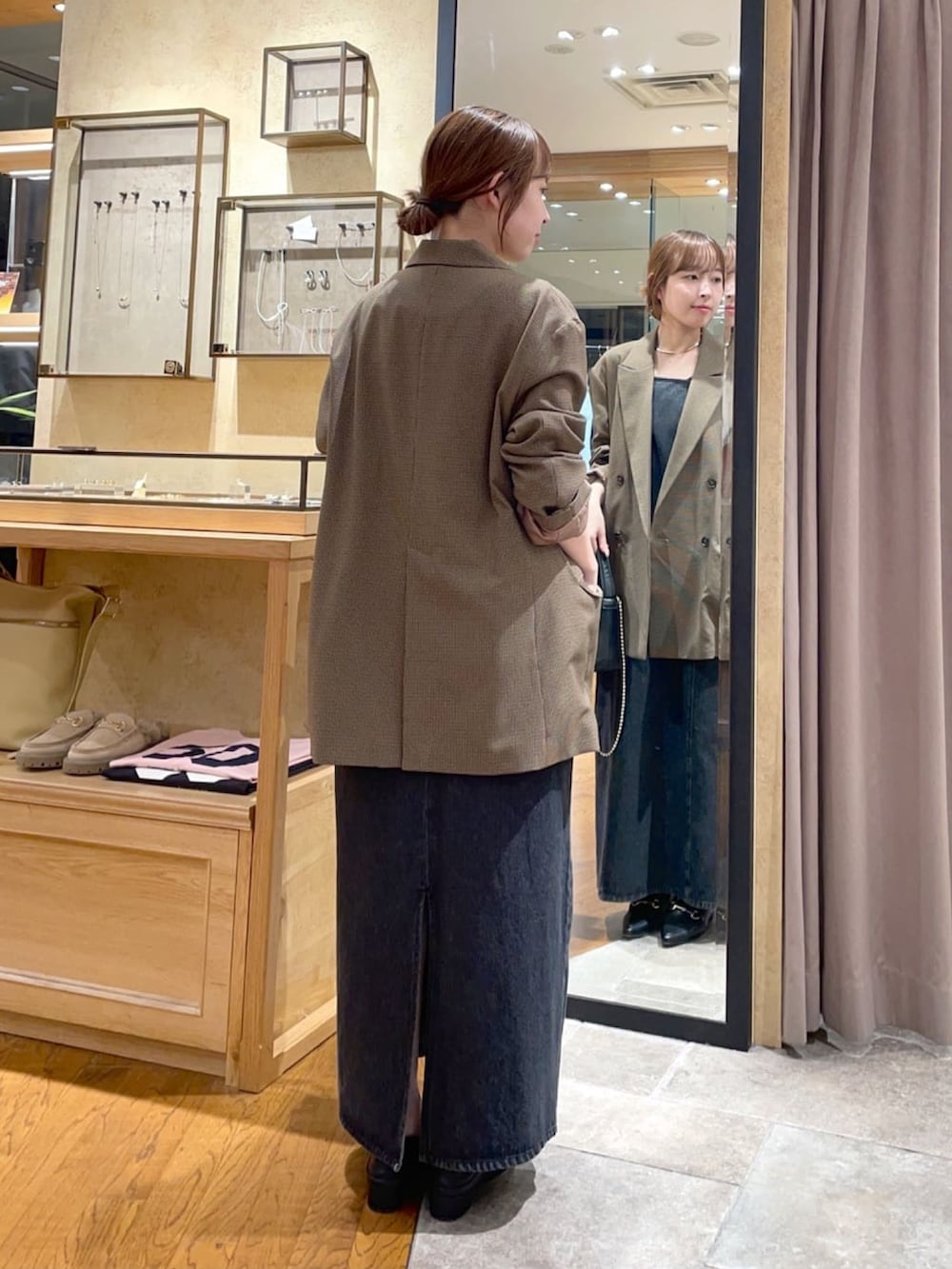 ブラウン系のテーラードジャケット、ブラック系のワンピース、ブラック系のハンドバッグを着用したレディースの秋コーディネートの4枚目の写真