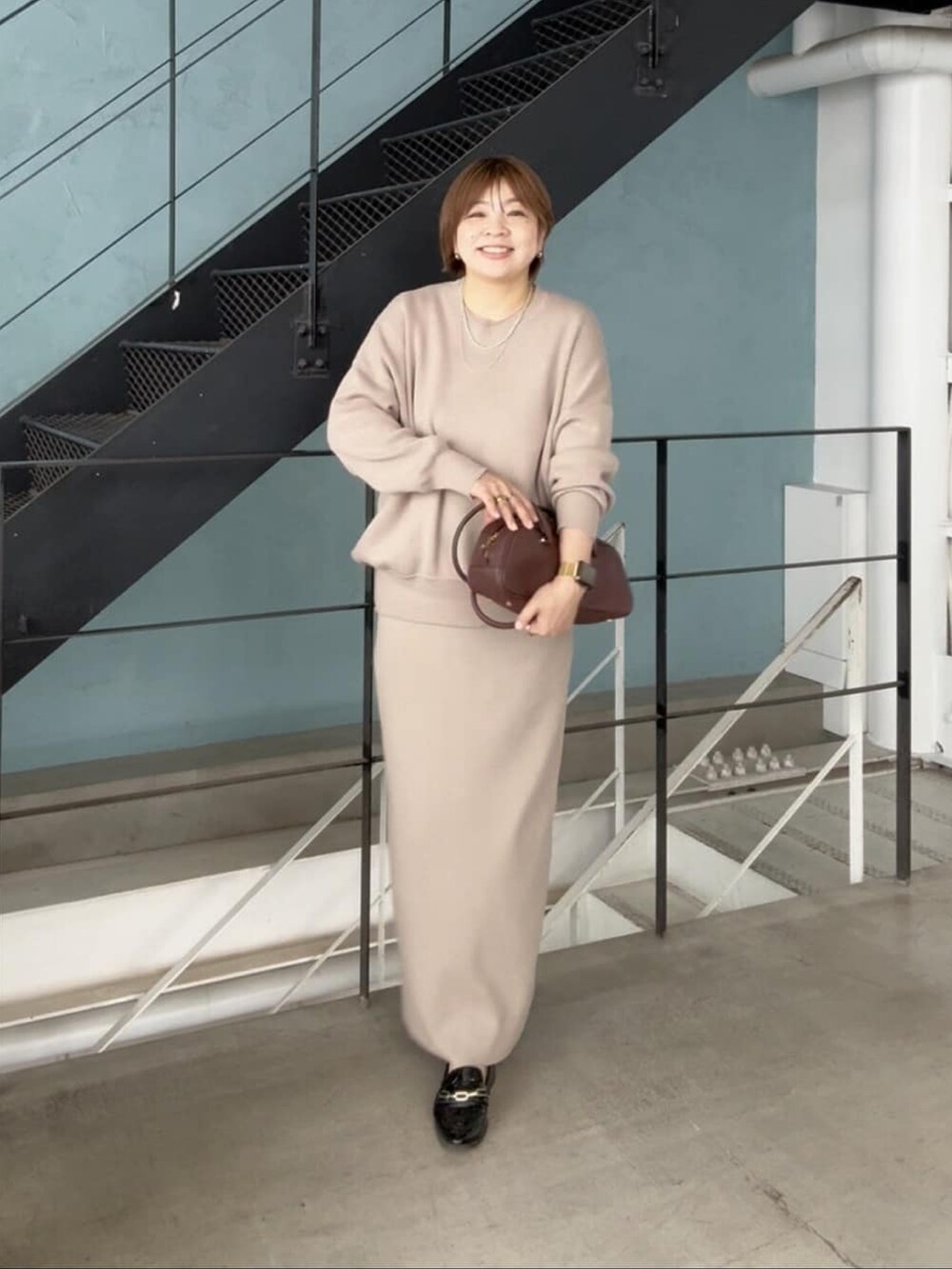 ブラウン系のショルダーバッグ、ブラウン系のニット/セーター、ブラウン系のスカートを着用したレディースの秋コーディネートの3枚目の写真