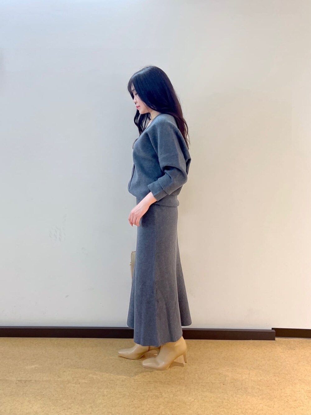 グレー系のカーディガン/ボレロ、グレー系のスカート、ベージュ系のブーツを着用したレディースの秋コーディネートの3枚目の写真