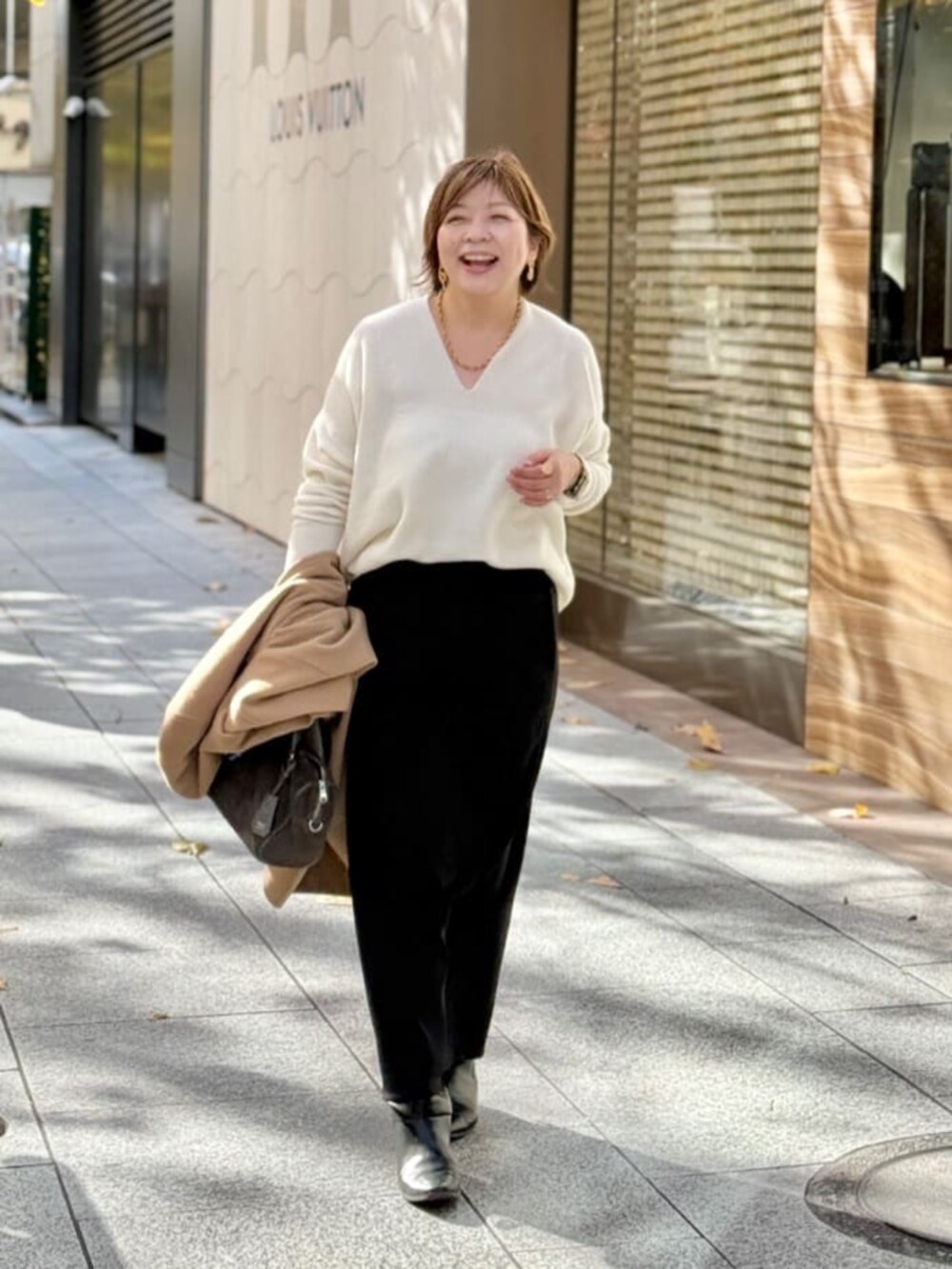 ホワイト系のニット/セーター、ブラック系のスカート、ゴールド系のネックレスを着用したレディースの冬コーディネートの2枚目の写真