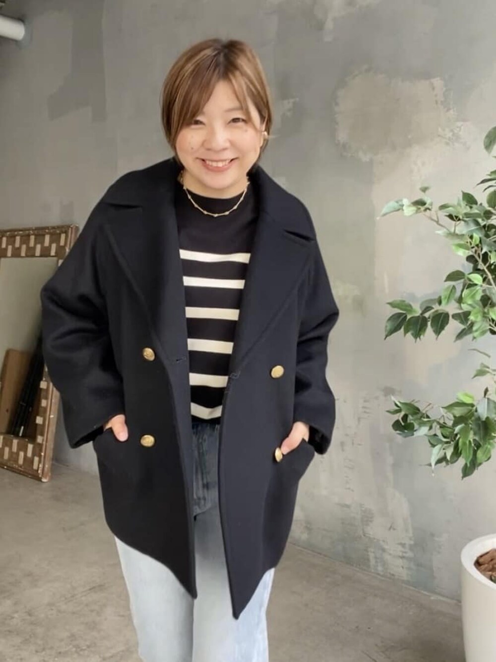 ブラック系のニット/セーター、ブルー系のデニムパンツ、ブラック系のピーコートを着用したレディースの秋コーディネートの4枚目の写真