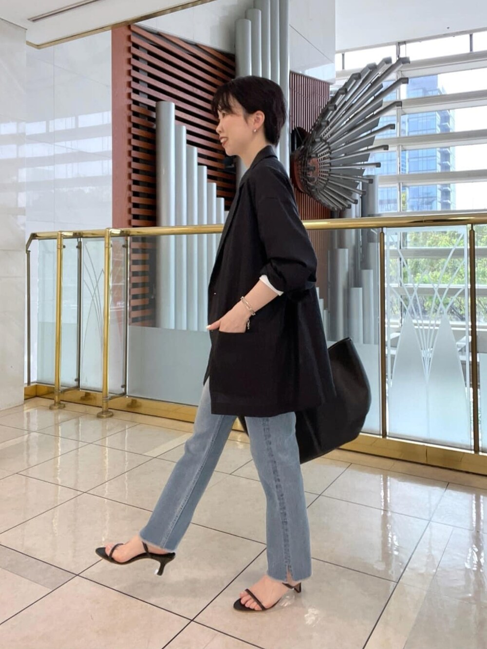 グリーン系のテーラードジャケット、ホワイト系のシャツ/ブラウス、ブラック系のサンダルを着用したレディースの春コーディネートの2枚目の写真