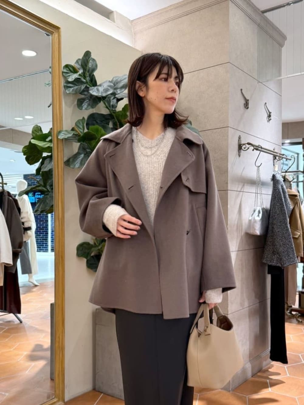 ブラウン系のその他アウター、グレー系のニット/セーター、ブラック系のスカートを着用したレディースの冬コーディネートの2枚目の写真