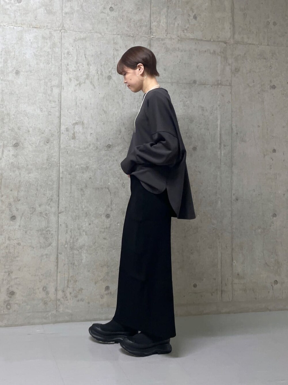 グレー系のTシャツ/カットソー、ブラック系のスカート、ブラック系のブーツを着用したレディースの冬コーディネートの2枚目の写真
