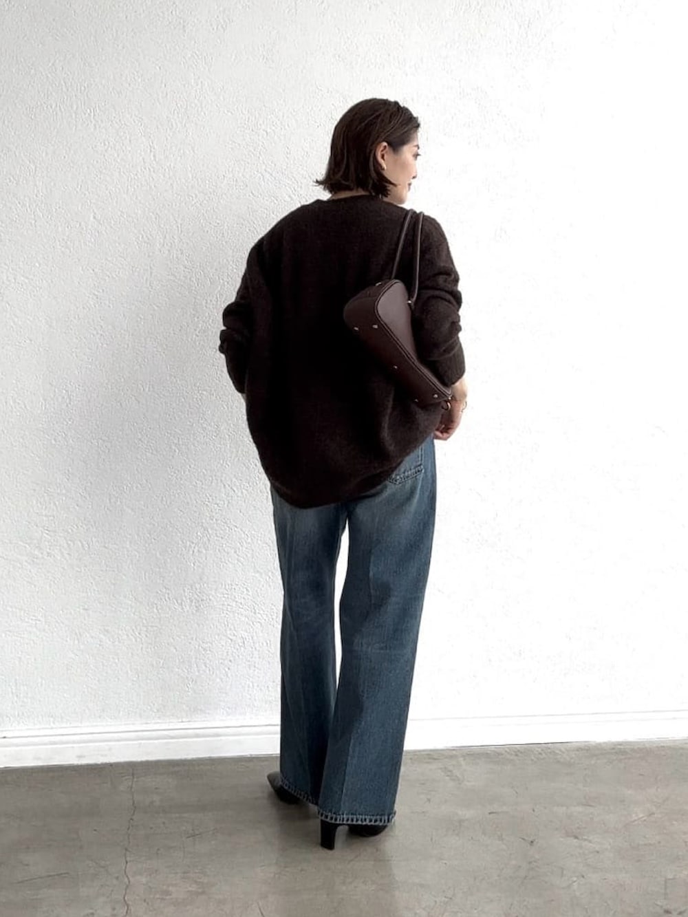 ブラウン系のカーディガン/ボレロ、ブルー系のデニムパンツ、ブラック系のブーツを着用したレディースの秋コーディネートの4枚目の写真