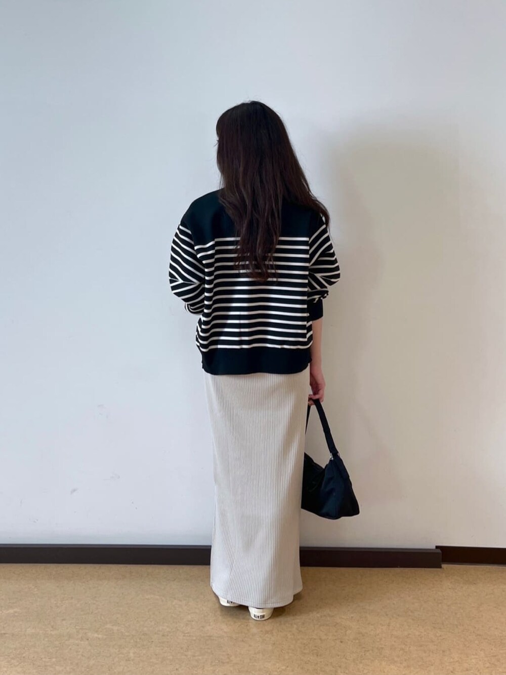 ベージュ系のワンピース、ブラック系のニット/セーターを着用したレディースの秋コーディネートの4枚目の写真