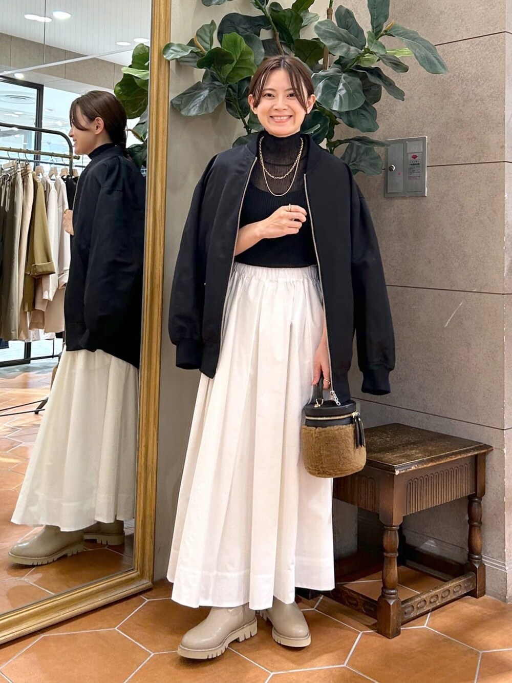ブラック系のニット/セーター、ホワイト系のスカート、ベージュ系のブーツを着用したレディースの秋コーディネートの4枚目の写真