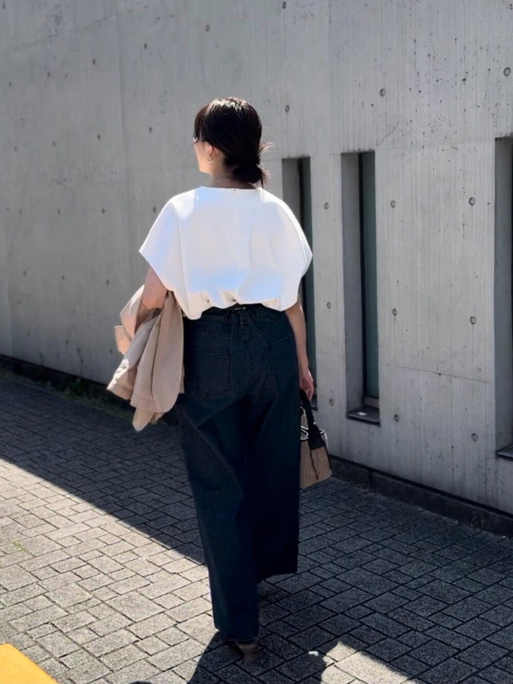 ブルー系のデニムパンツ、ブラック系のハンドバッグ、ブラック系のサンダルを着用したレディースの春コーディネートの3枚目の写真