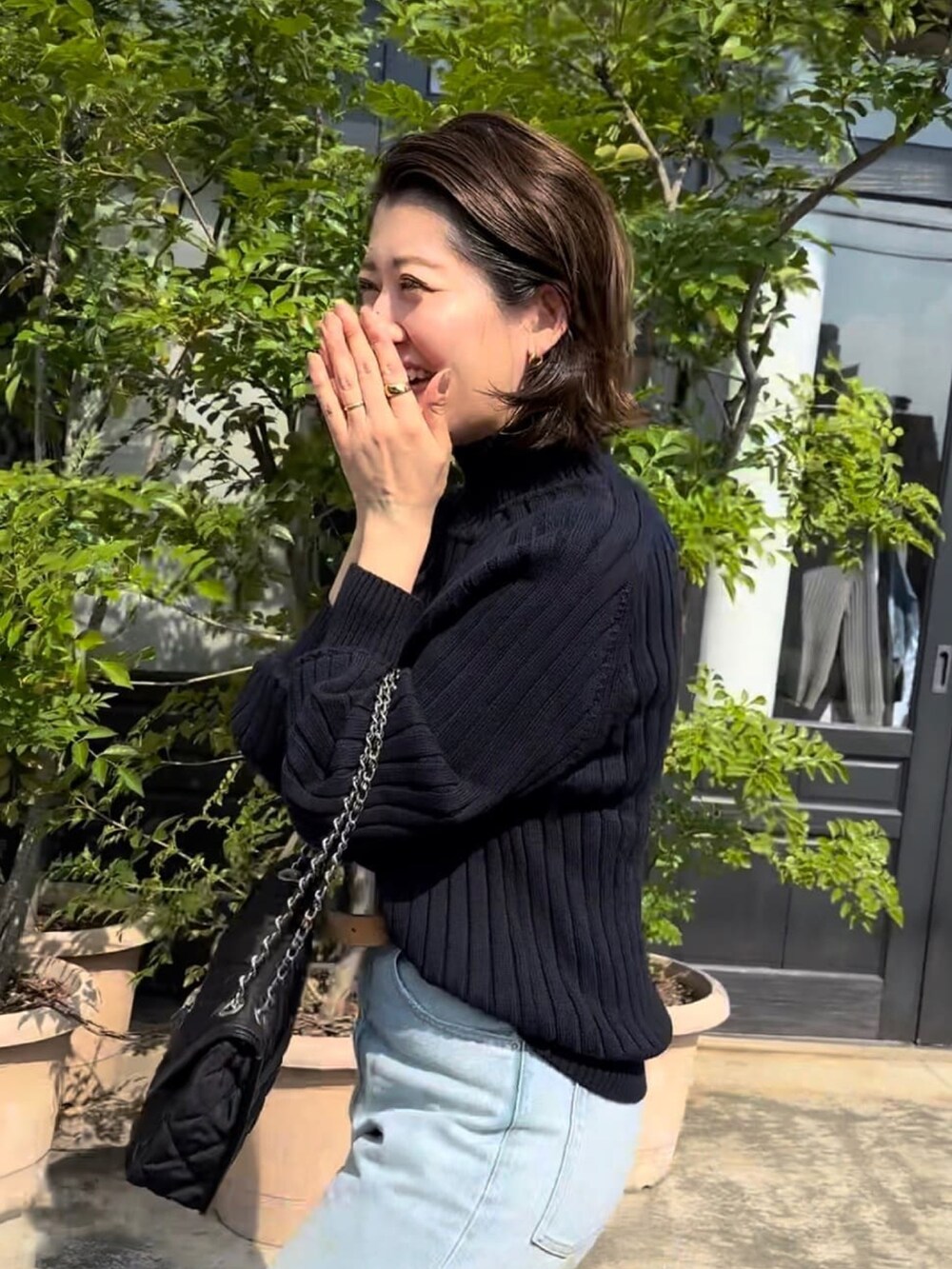 ブルー系のニット/セーター、ブラック系のショルダーバッグ、ブルー系のデニムパンツを着用したレディースの冬コーディネートの4枚目の写真