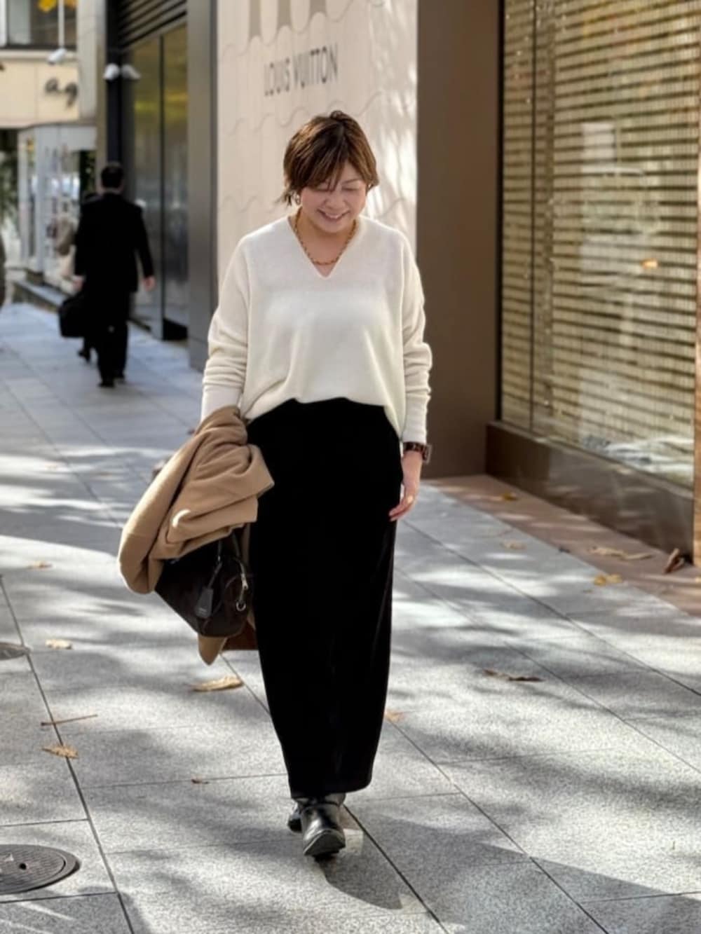 ホワイト系のニット/セーター、ブラック系のスカート、ゴールド系のネックレスを着用したレディースの冬コーディネートの3枚目の写真