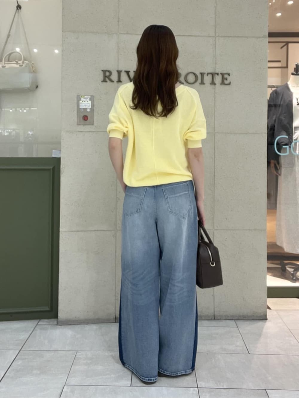 ブラウン系のボストンバッグ、イエロー系のニット/セーター、ブルー系のデニムパンツを着用したレディースの春コーディネートの3枚目の写真