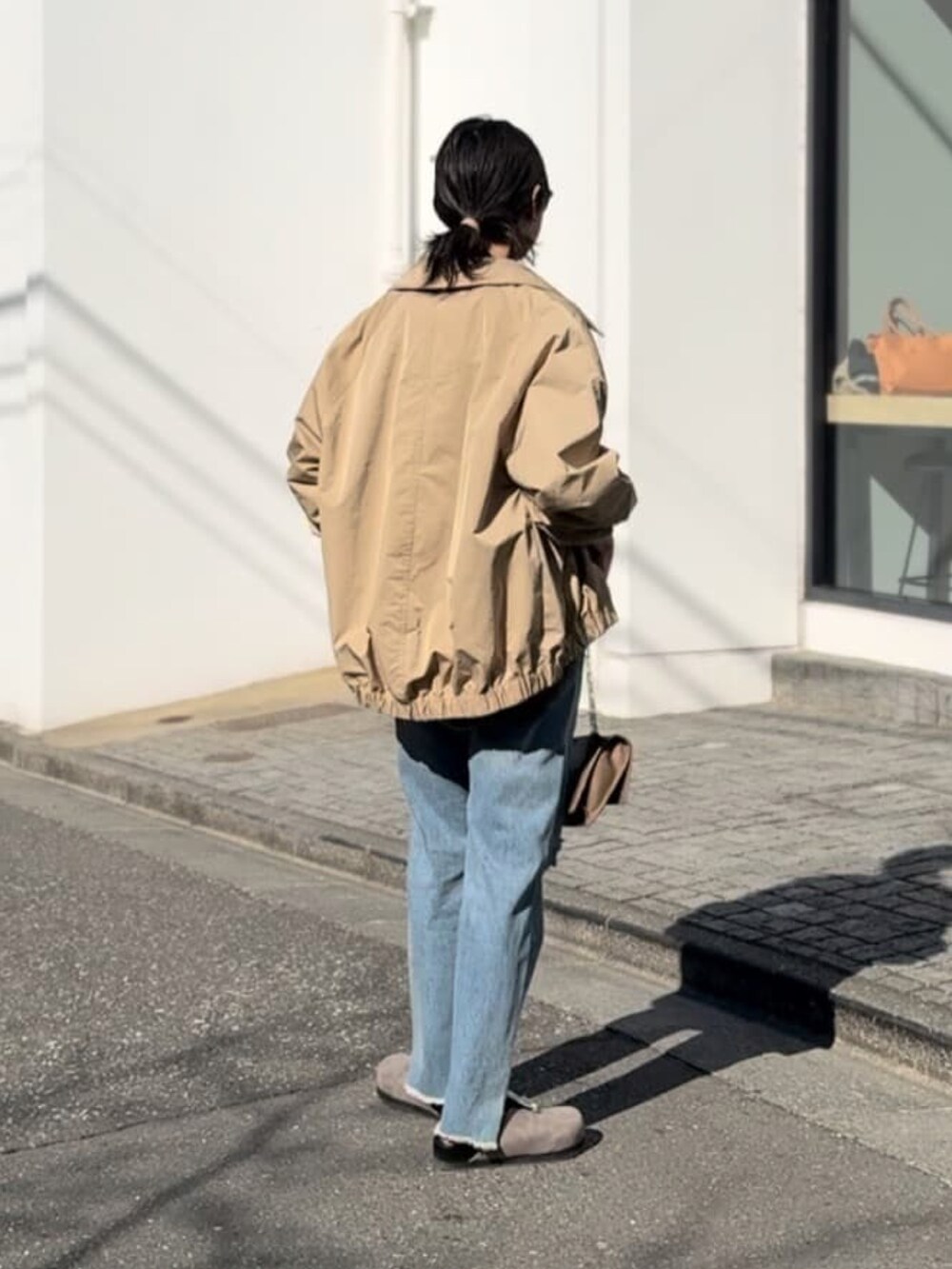 グリーン系のシャツ/ブラウス、ベージュ系のブルゾン、ブルー系のデニムパンツを着用したレディースの春コーディネートの3枚目の写真