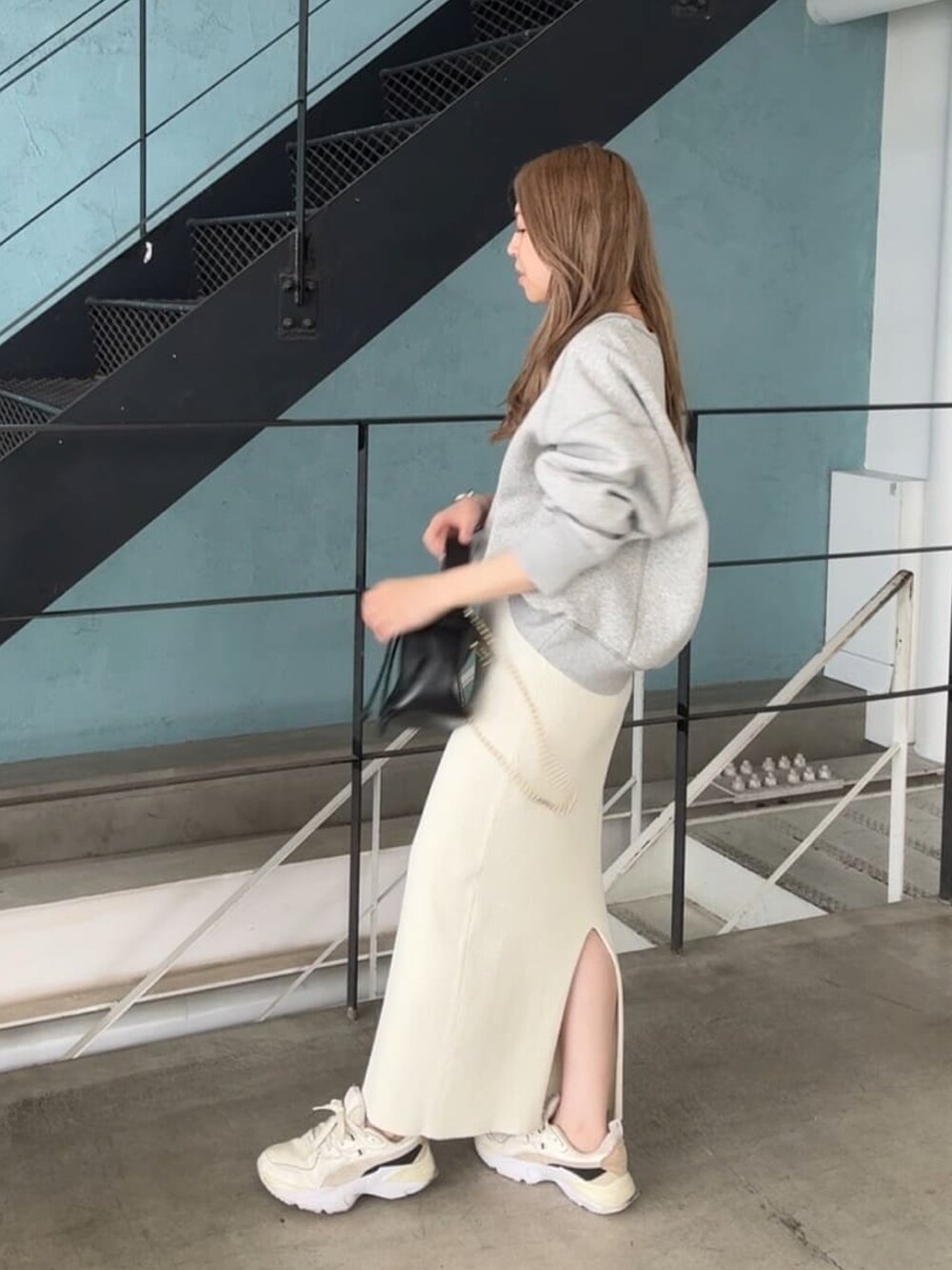 グレー系のスウェット、ホワイト系のスカート、ブラック系のハンドバッグを着用したレディースの秋コーディネートの2枚目の写真