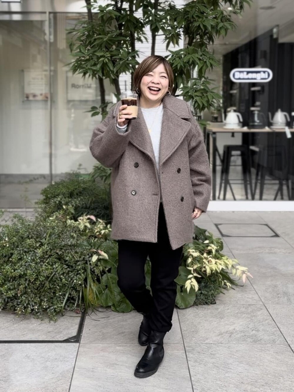 ブラウン系のその他アウター、ブラック系のスウェットパンツ、ブラック系のブーツを着用したレディースの冬コーディネートの2枚目の写真