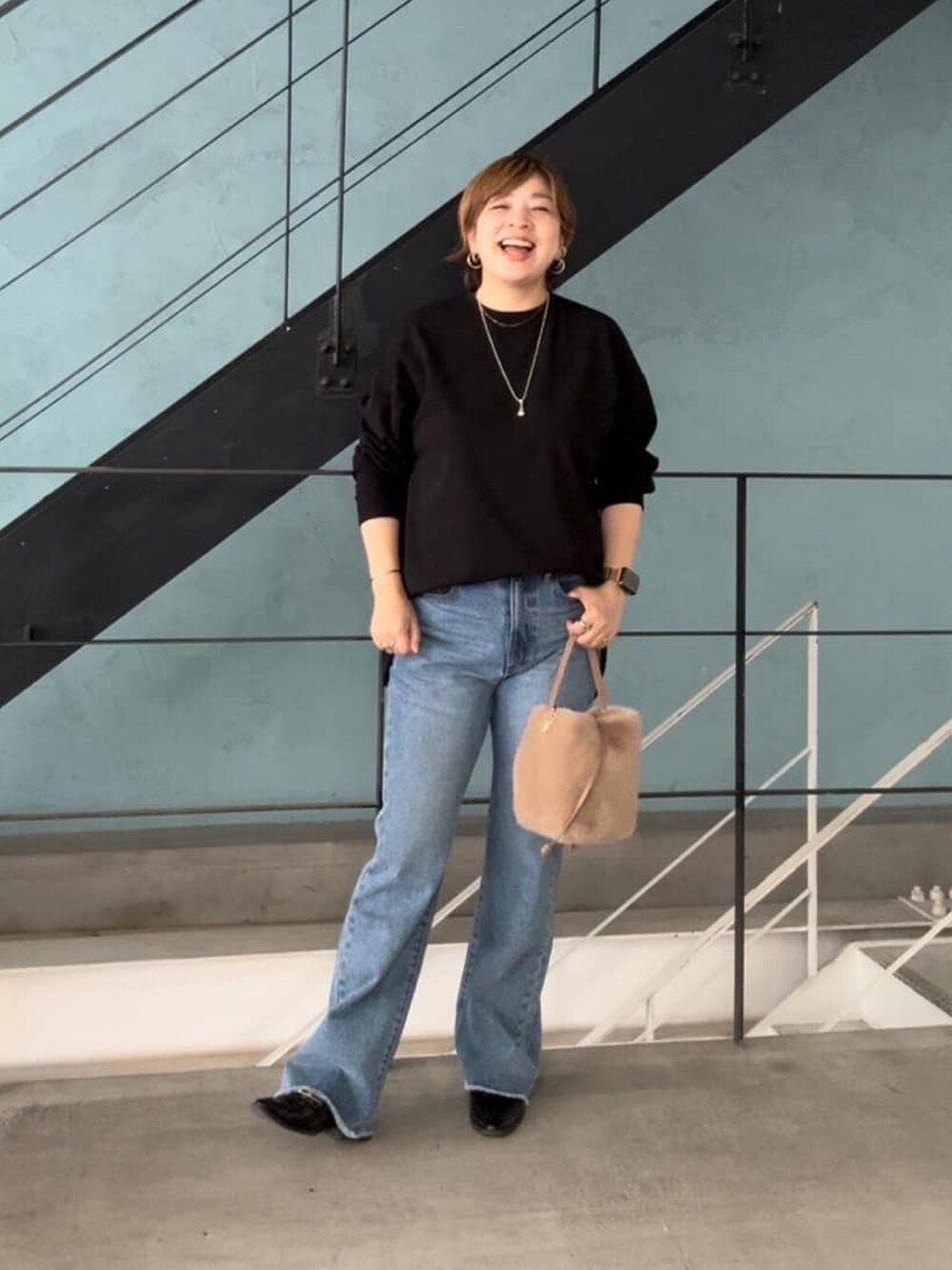 ホワイト系のTシャツ/カットソー、ブルー系のデニムパンツ、ベージュ系のハンドバッグを着用したレディースの秋コーディネートの2枚目の写真