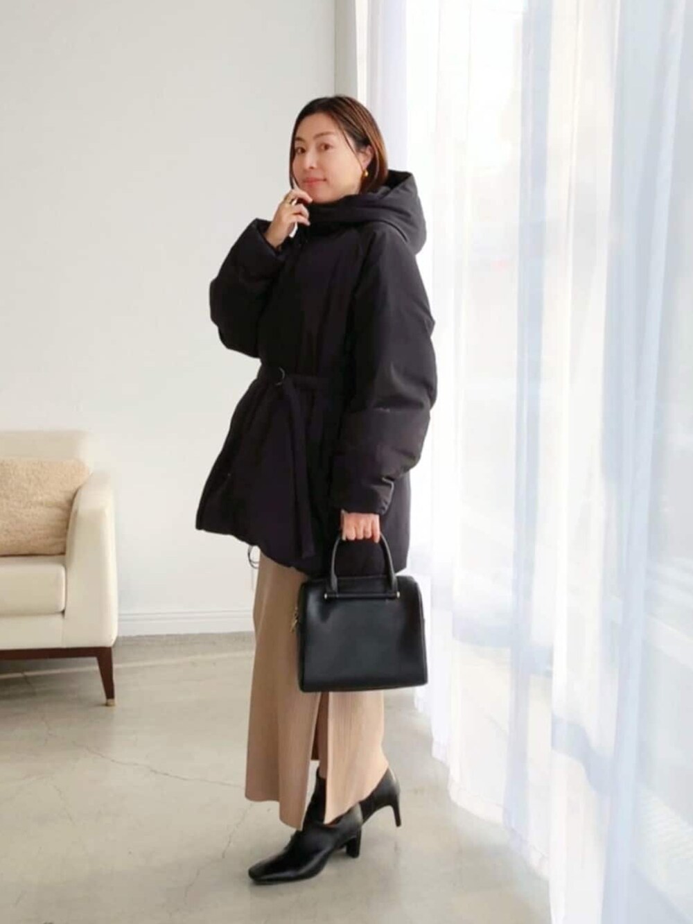 ブラック系のダウンジャケット/コート、ブラウン系のワンピース、ブラック系のブーツを着用したレディースの冬コーディネートの2枚目の写真