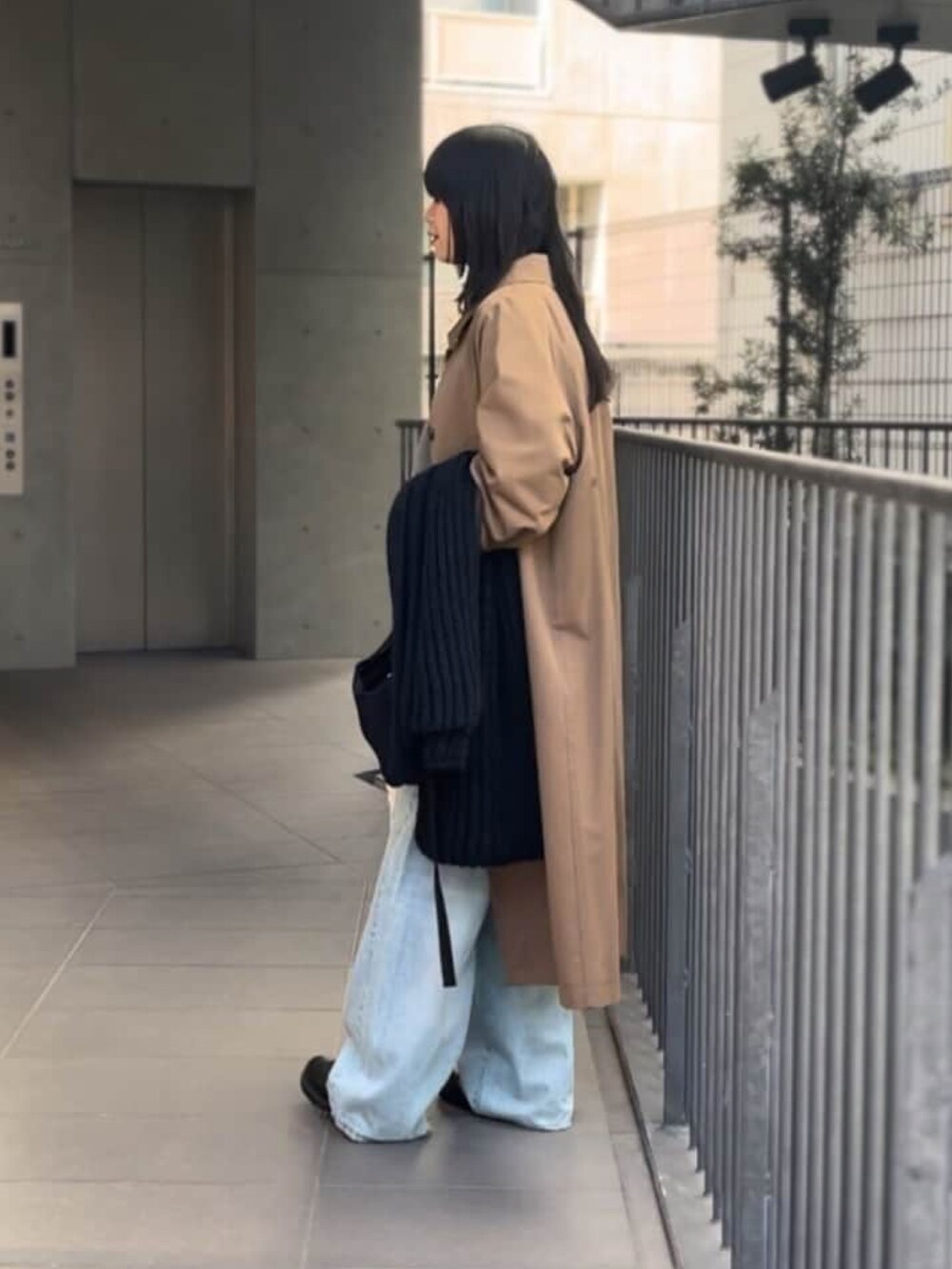 ベージュ系のニット/セーター、ブルー系のデニムパンツ、ブラウン系のステンカラーコートを着用したレディースの冬コーディネートの2枚目の写真