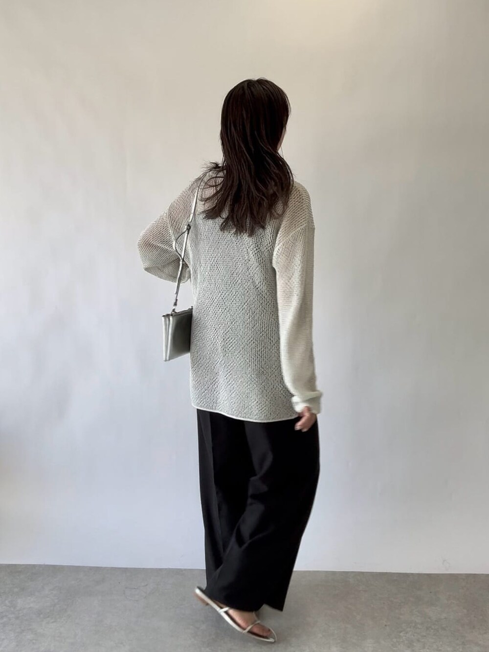 ブルー系のニット/セーター、グレー系のスラックスを着用したレディースの春コーディネートの3枚目の写真