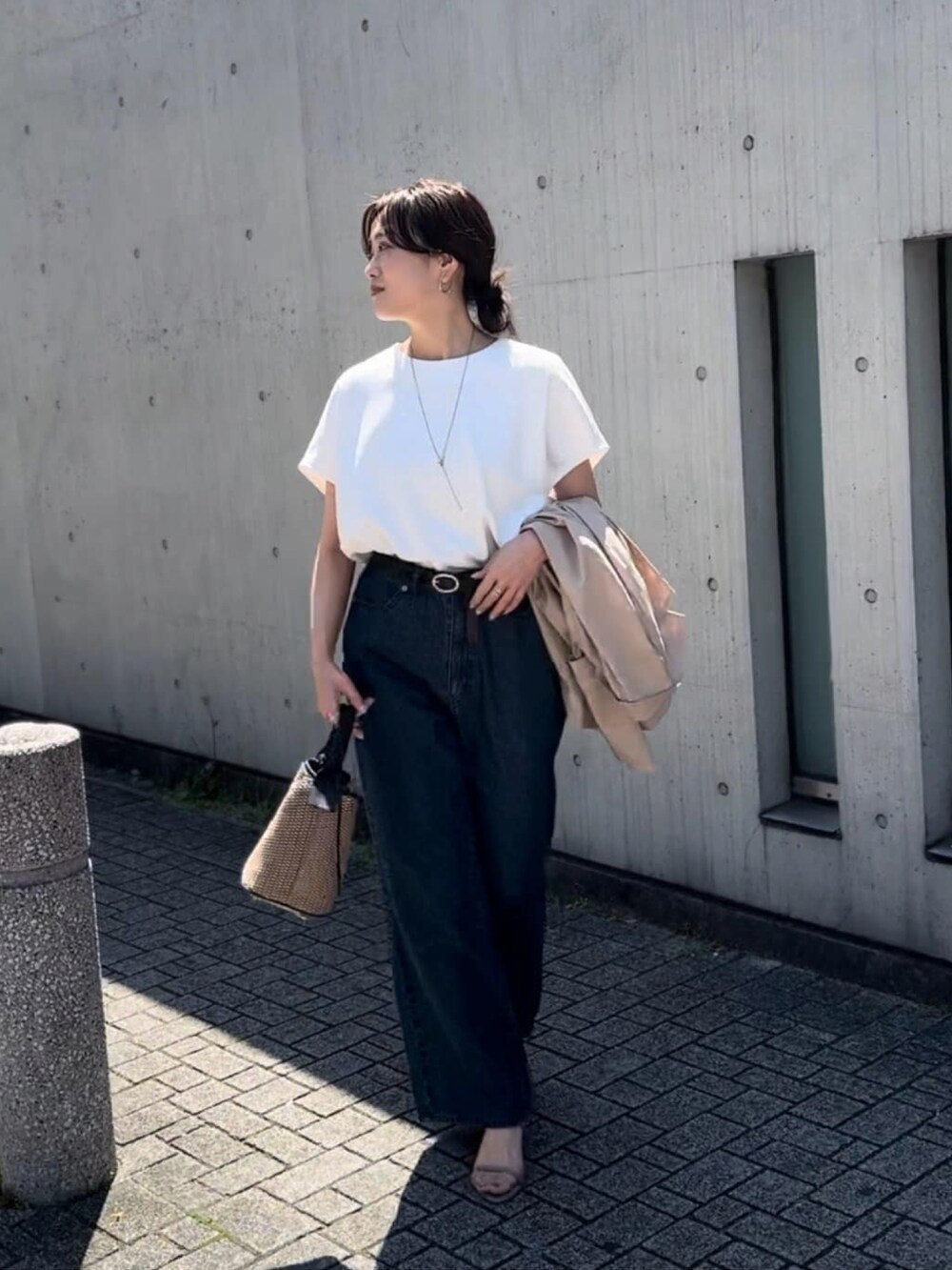 ブルー系のデニムパンツ、ブラック系のハンドバッグ、ブラック系のサンダルを着用したレディースの春コーディネートの2枚目の写真