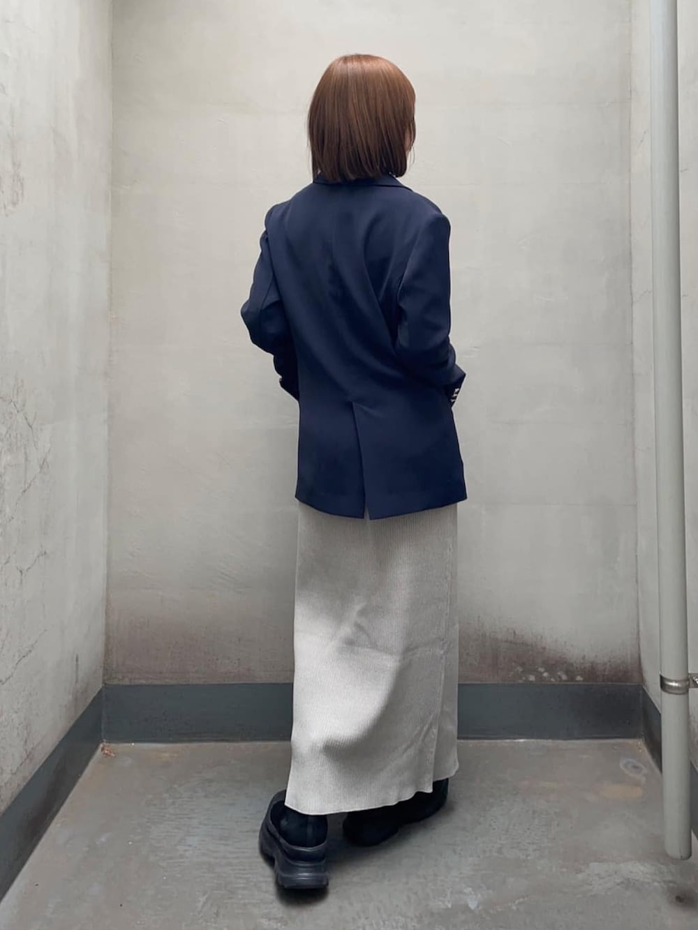 ブルー系のテーラードジャケット、グレー系のワンピース、ブラック系のブーツを着用したレディースの春コーディネートの3枚目の写真