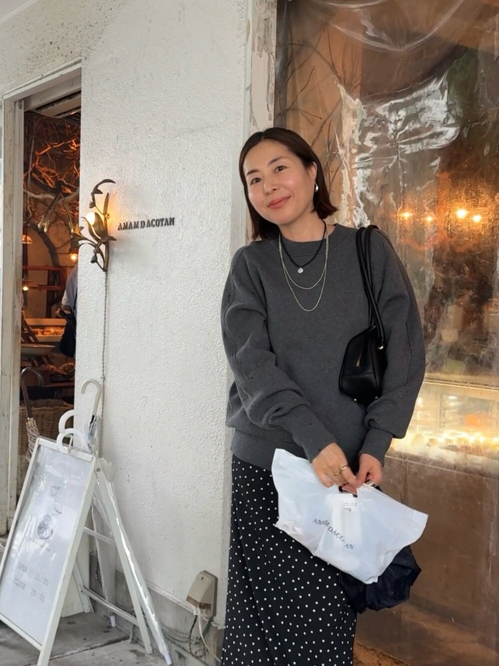 グレー系のニット/セーター、ブラック系のスカート、ブラック系のブーツを着用したレディースの秋コーディネートの3枚目の写真