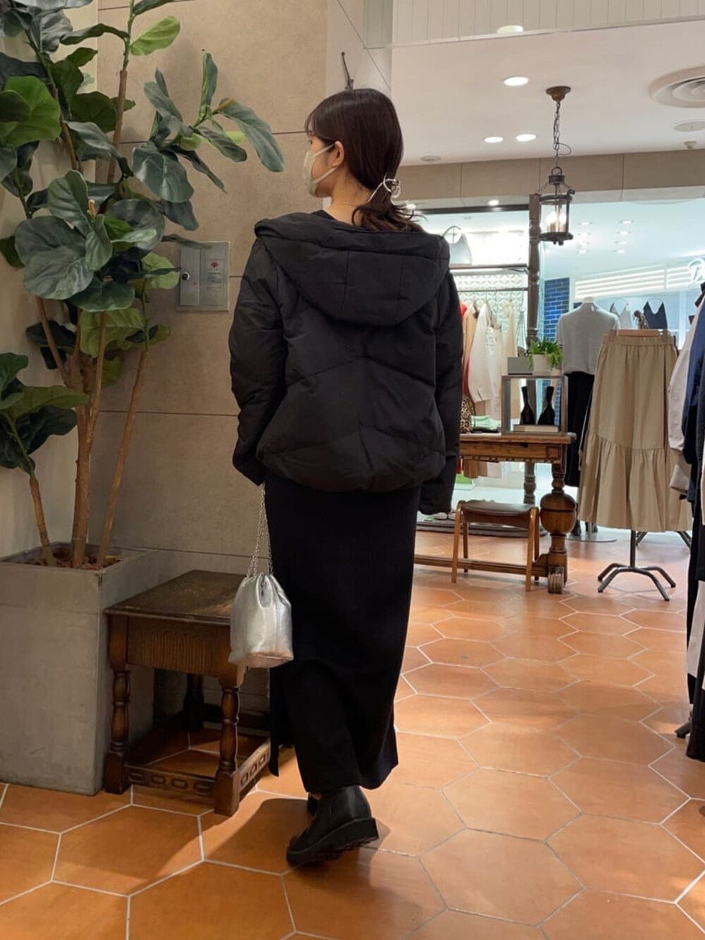 シルバー系のショルダーバッグ、ブラック系のワンピース、ブラック系のブーツを着用したレディースの冬コーディネートの2枚目の写真