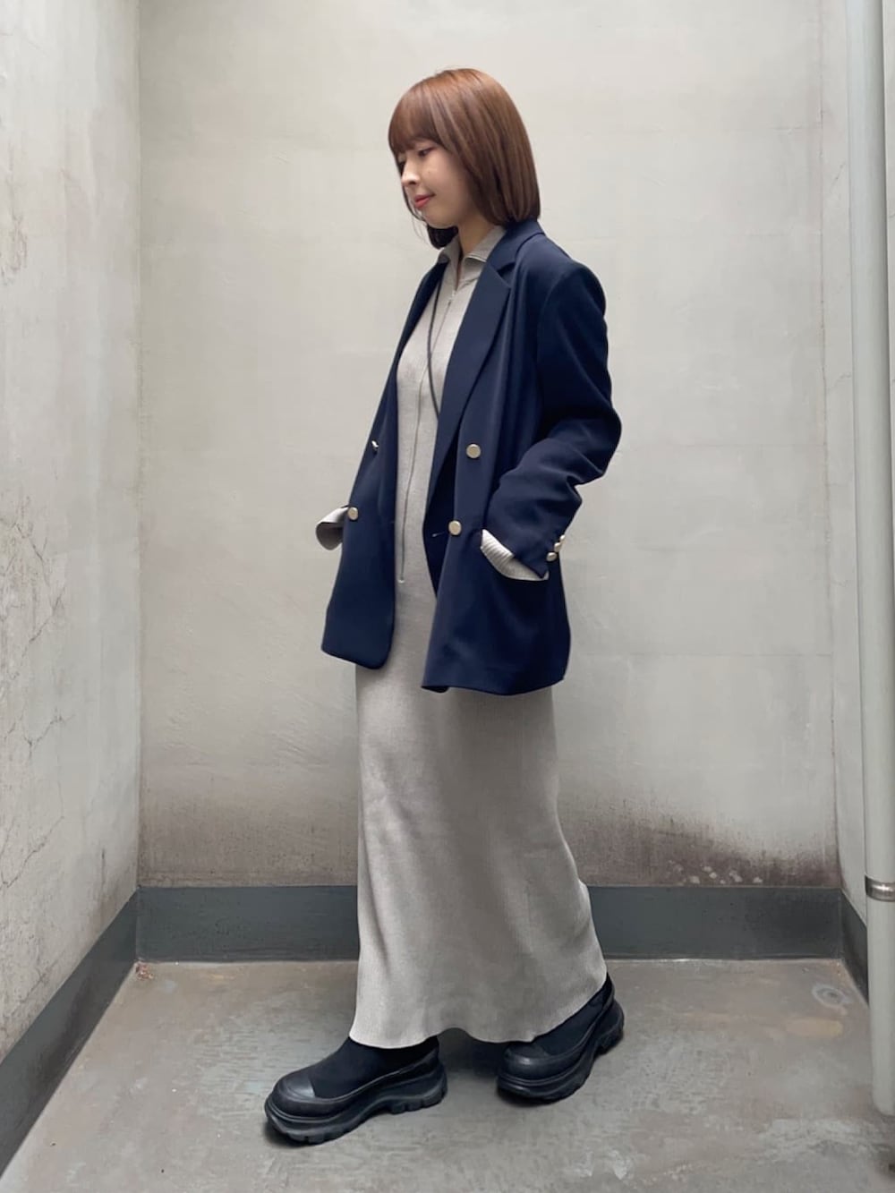 ブルー系のテーラードジャケット、グレー系のワンピース、ブラック系のブーツを着用したレディースの春コーディネートの2枚目の写真