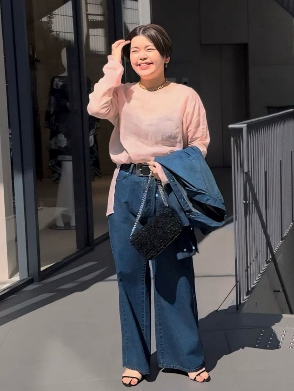 ピンク系のシャツ/ブラウス、ブラック系のショルダーバッグ、ブルー系のデニムパンツを着用したレディースの春コーディネートの2枚目の写真