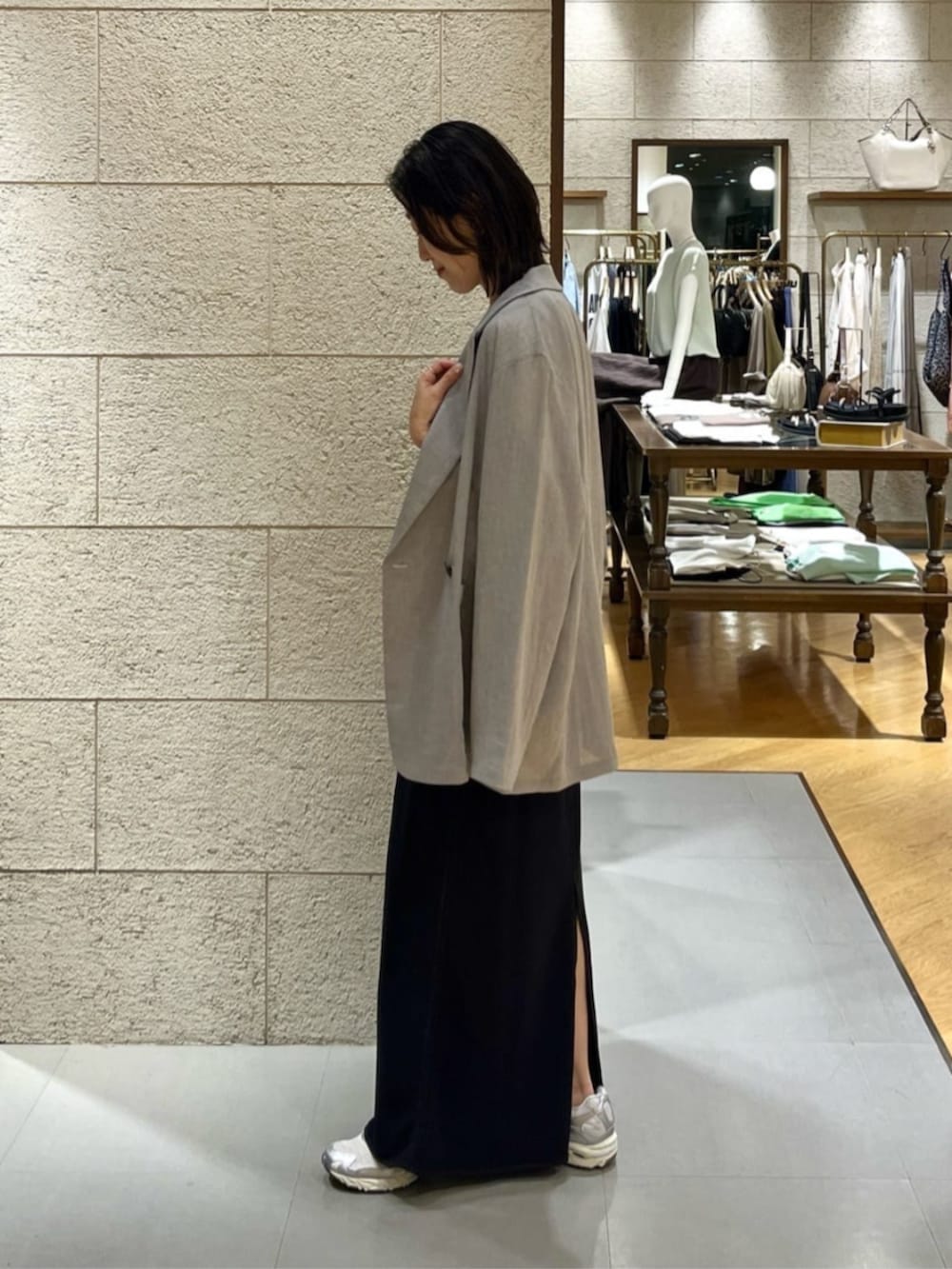 グレー系のテーラードジャケット、ホワイト系のTシャツ/カットソー、ブラック系のスカートを着用したレディースの夏コーディネートの2枚目の写真