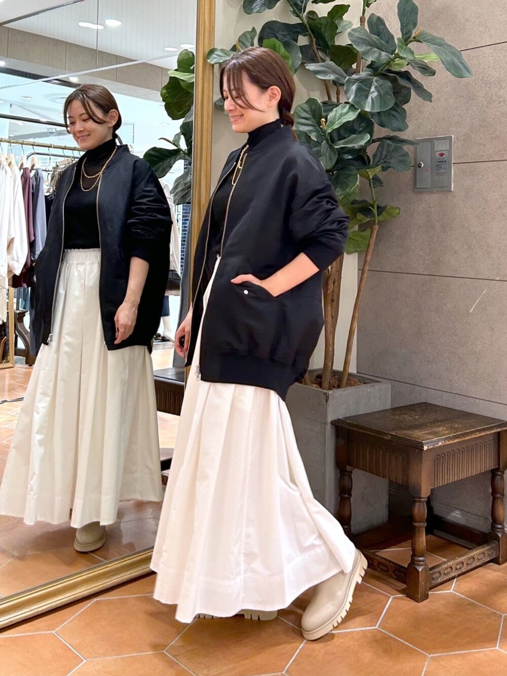 ブラック系のニット/セーター、ホワイト系のスカート、ベージュ系のブーツを着用したレディースの秋コーディネートの2枚目の写真