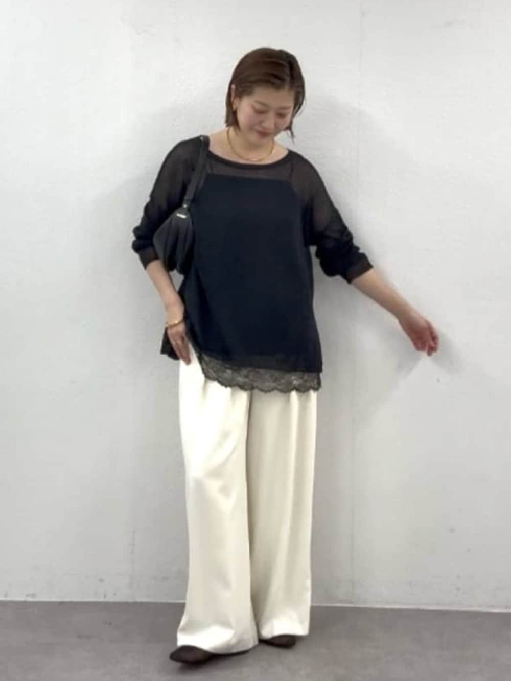 ホワイト系のスラックス、ブラック系のニット/セーター、ブラック系のキャミソールを着用したレディースの春コーディネートの3枚目の写真