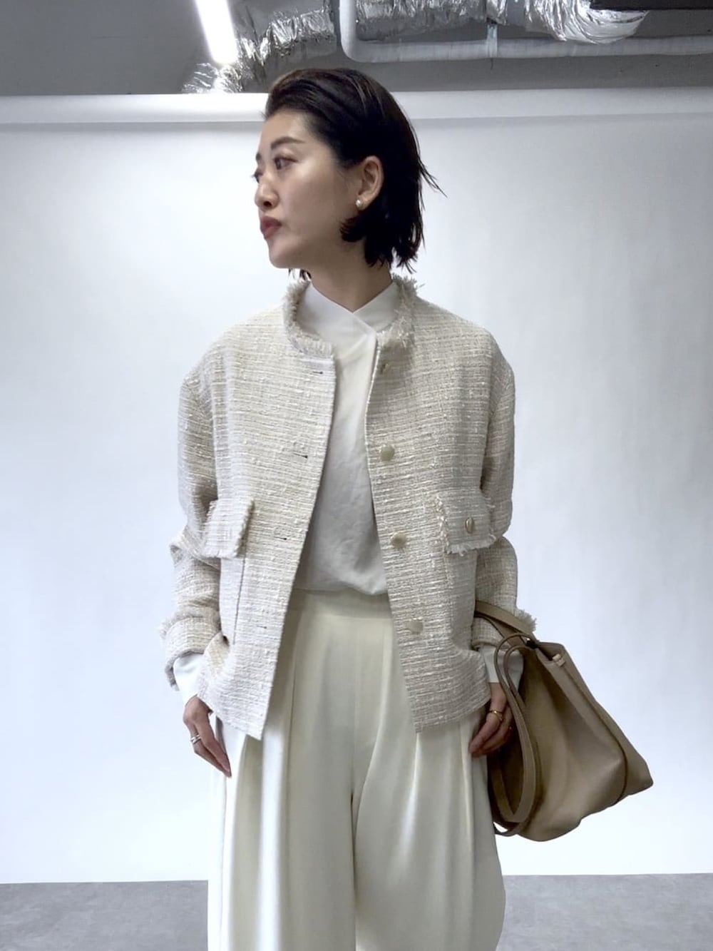 ホワイト系のスラックス、ベージュ系のノーカラージャケット、ベージュ系のトートバッグを着用したレディースの冬コーディネートの5枚目の写真