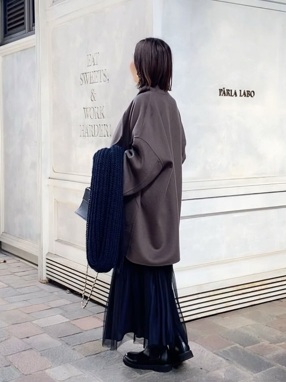 ブラウン系のその他アウター、ブラック系のスカート、ブラック系のハンドバッグを着用したレディースの秋コーディネートの2枚目の写真