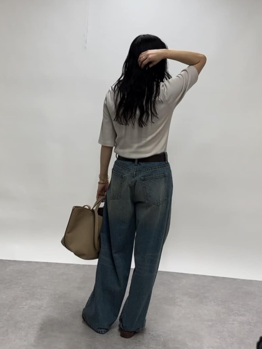 グレー系のTシャツ/カットソー、ブルー系のデニムパンツ、ベージュ系のトートバッグを着用したレディースの春コーディネートの3枚目の写真