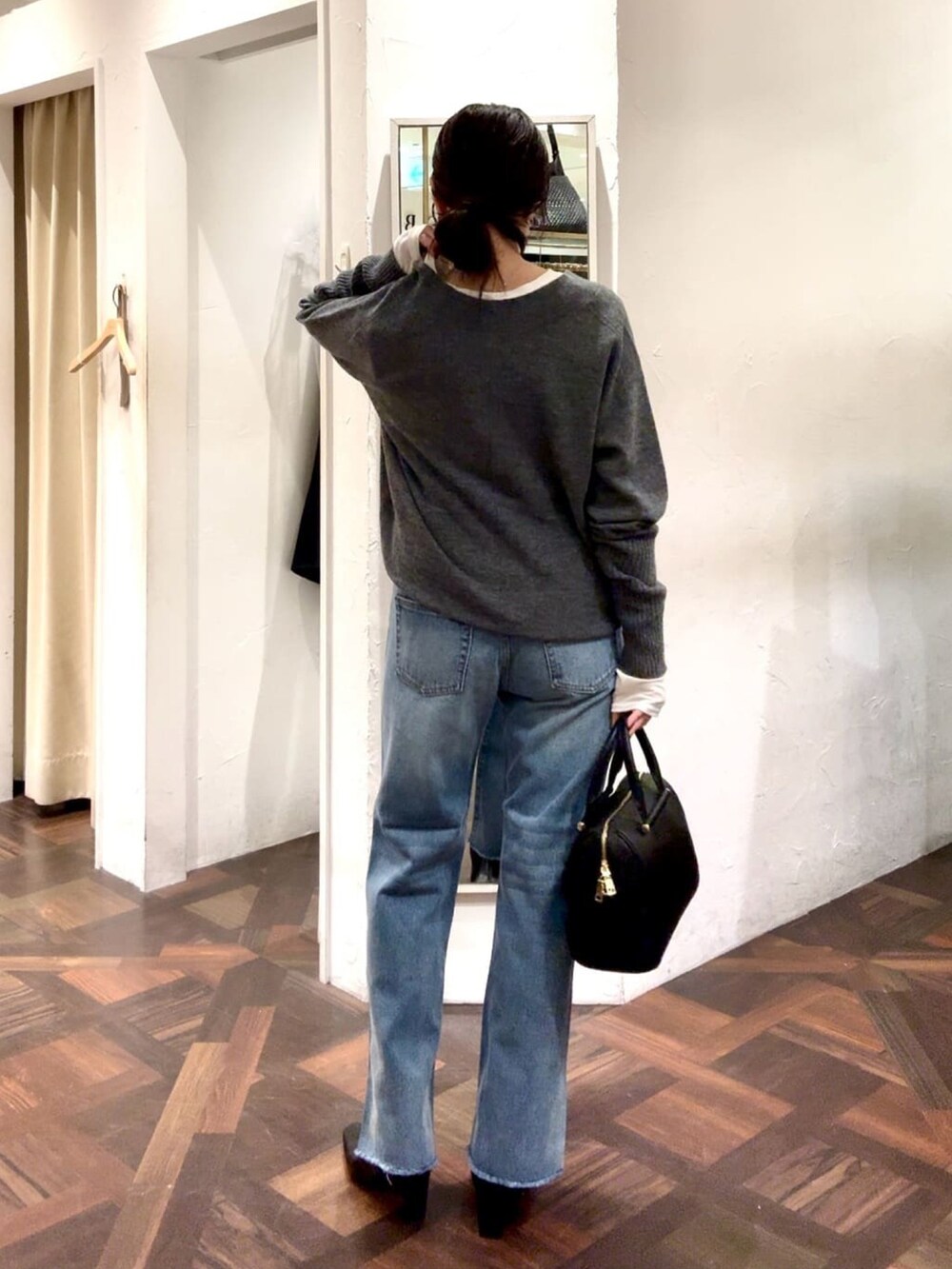 グレー系のニット/セーター、ブルー系のデニムパンツ、ブラック系のボストンバッグを着用したレディースの冬コーディネートの3枚目の写真