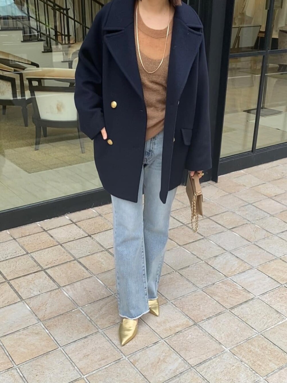 ブルー系のピーコート、ブルー系のデニムパンツ、ゴールド系のパンプスを着用したレディースの冬コーディネートの4枚目の写真