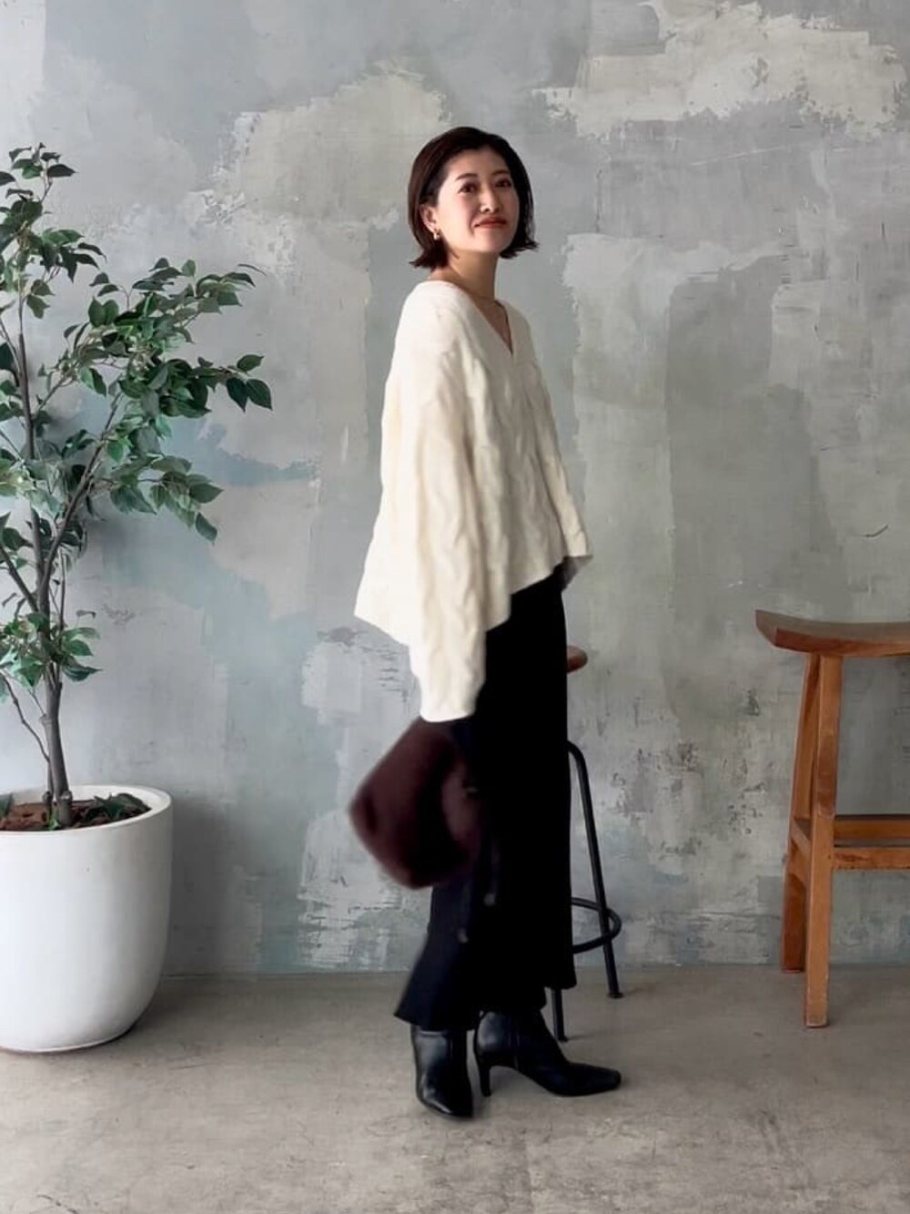 ホワイト系のニット/セーター、ブラック系のスカート、ブラウン系のハンドバッグを着用したレディースの秋コーディネートの2枚目の写真