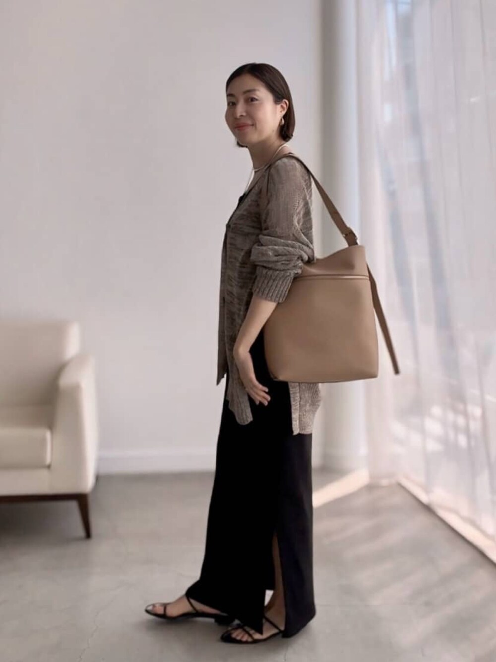 ブラウン系のカーディガン/ボレロ、ブラック系のワンピース、ブラック系のサンダルを着用したレディースの夏コーディネートの2枚目の写真