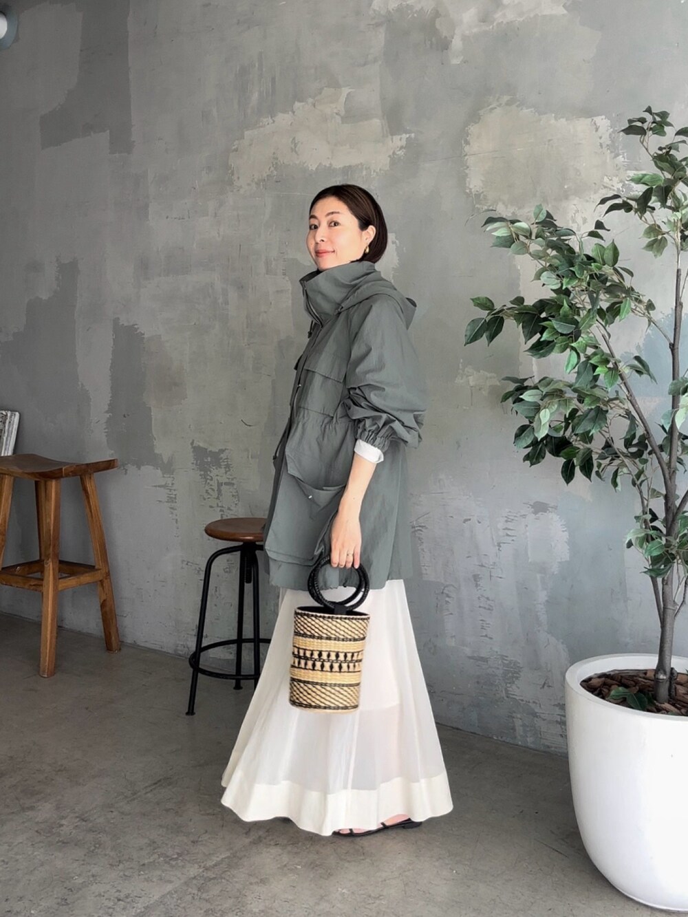 グリーン系のマウンテンパーカー、ベージュ系のスカート、ブラック系のサンダルを着用したレディースの夏コーディネートの2枚目の写真