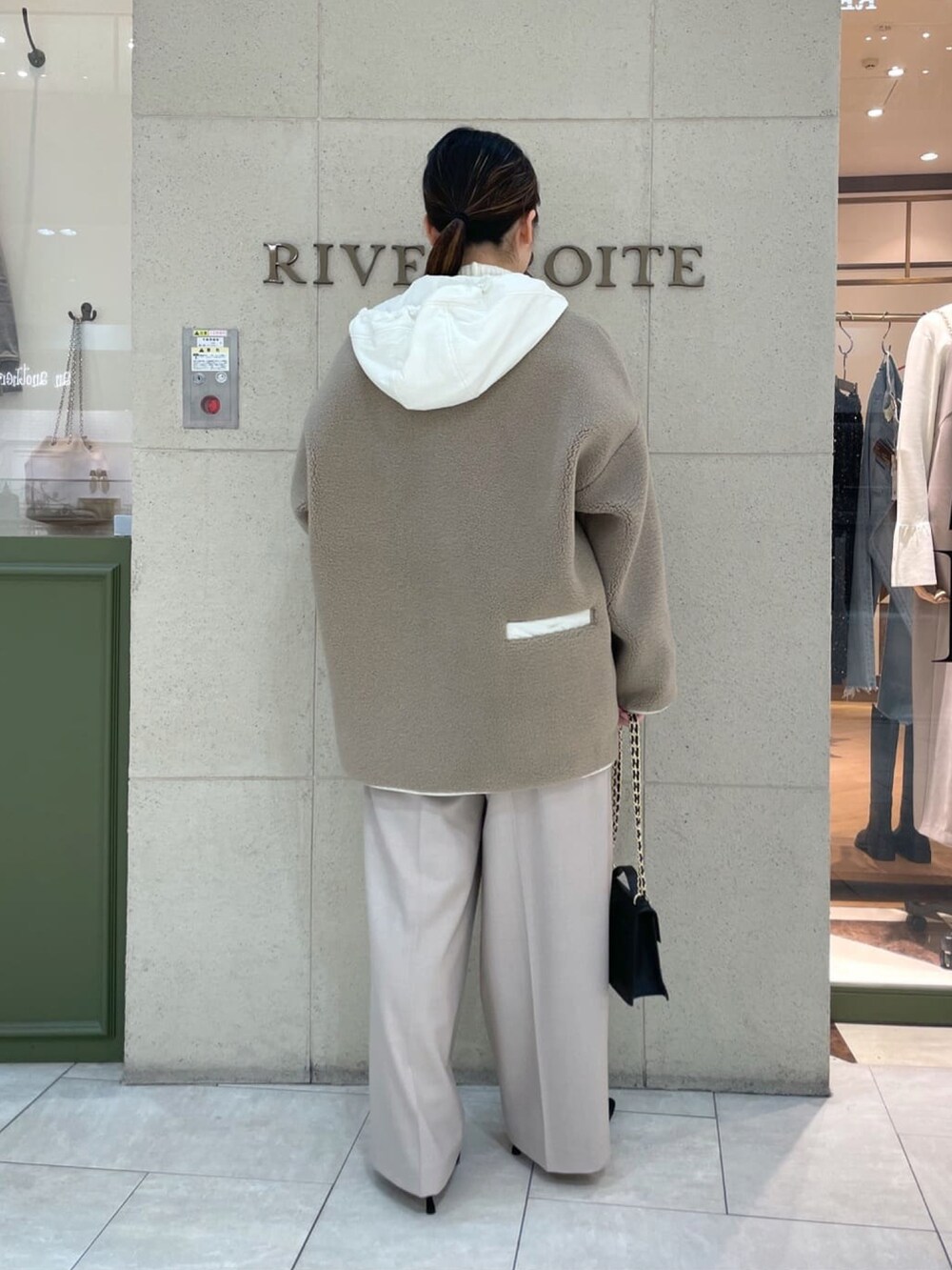 ブラック系のハンドバッグ、ベージュ系のその他アウター、ホワイト系のニット/セーターを着用したレディースの冬コーディネートの4枚目の写真