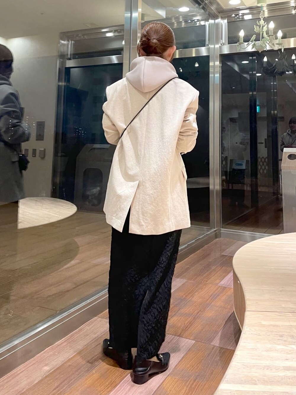 ブラック系のショルダーバッグ、ベージュ系のテーラードジャケット、ベージュ系のパーカーを着用したレディースの冬コーディネートの3枚目の写真