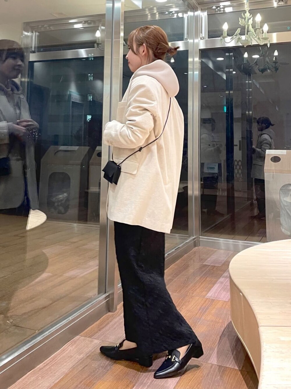 ブラック系のショルダーバッグ、ベージュ系のテーラードジャケット、ベージュ系のパーカーを着用したレディースの冬コーディネートの2枚目の写真