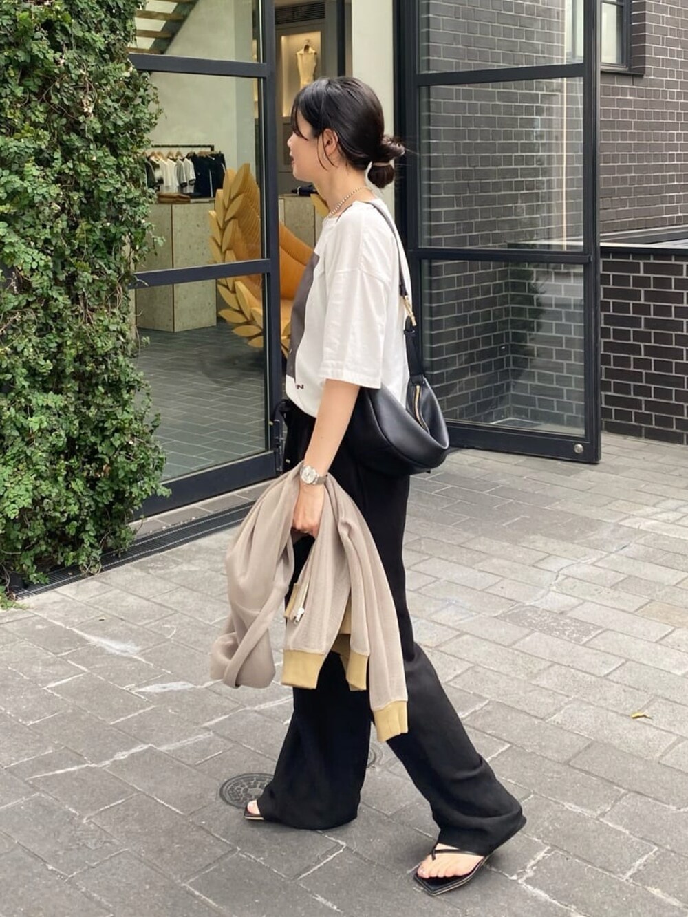 ブラック系のスラックス、ブラック系のサンダル、ブラウン系のTシャツ/カットソーを着用したレディースの夏コーディネートの2枚目の写真