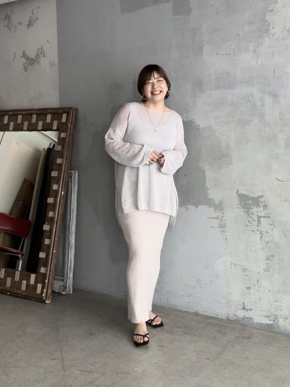 グレー系のニット/セーター、ホワイト系のスカート、グレー系のタンクトップを着用したレディースの春コーディネートの3枚目の写真