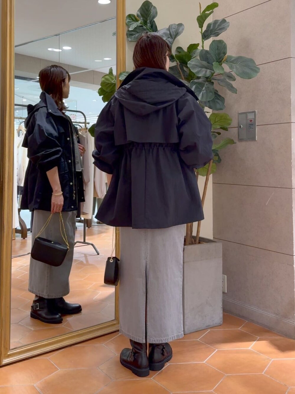 グレー系のシャツ/ブラウス、グレー系のデニムスカート、ブラック系のマウンテンパーカーを着用したレディースの冬コーディネートの4枚目の写真