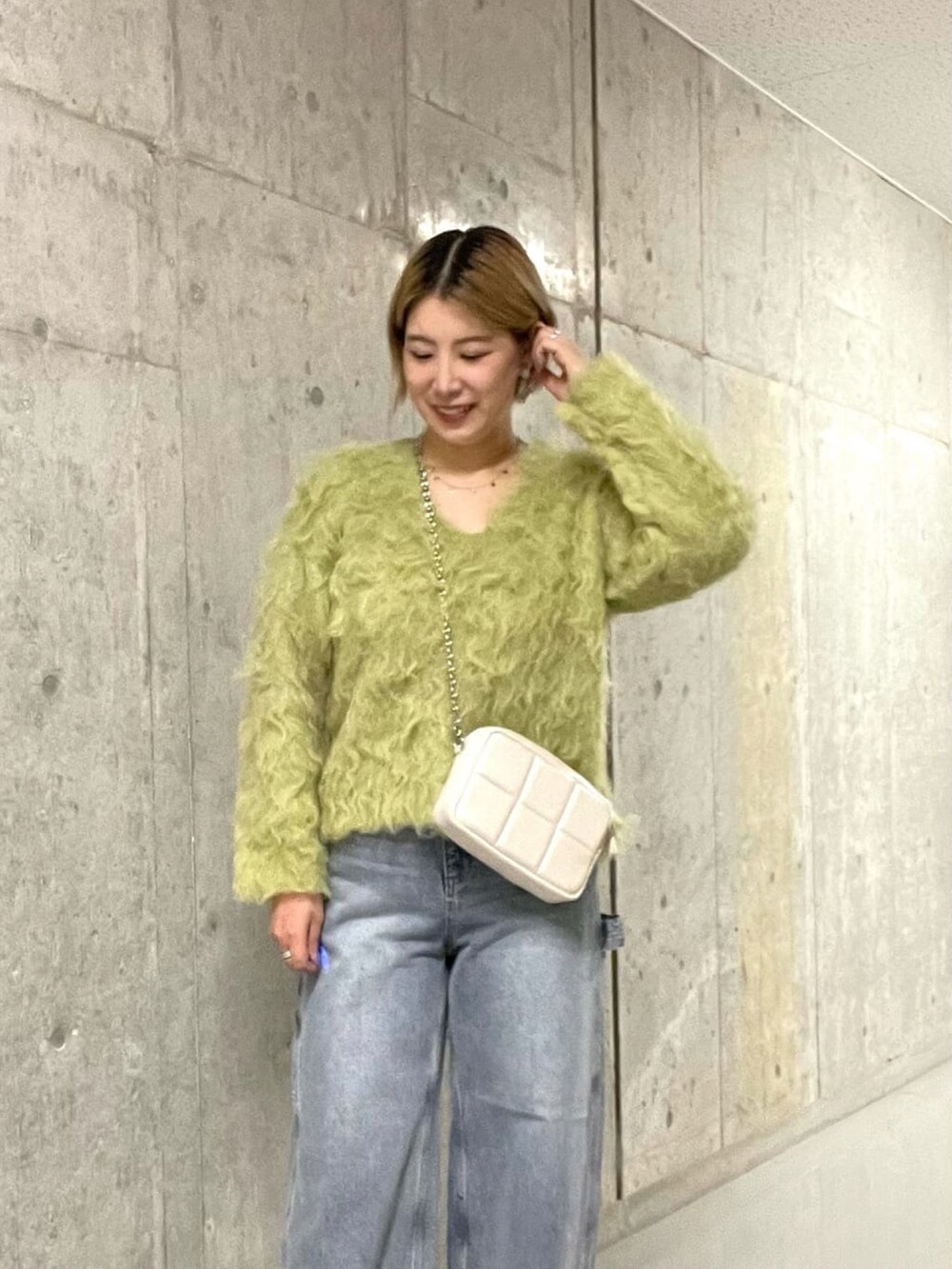 グリーン系のニット/セーター、ブルー系のデニムパンツを着用したレディースの冬コーディネートの2枚目の写真