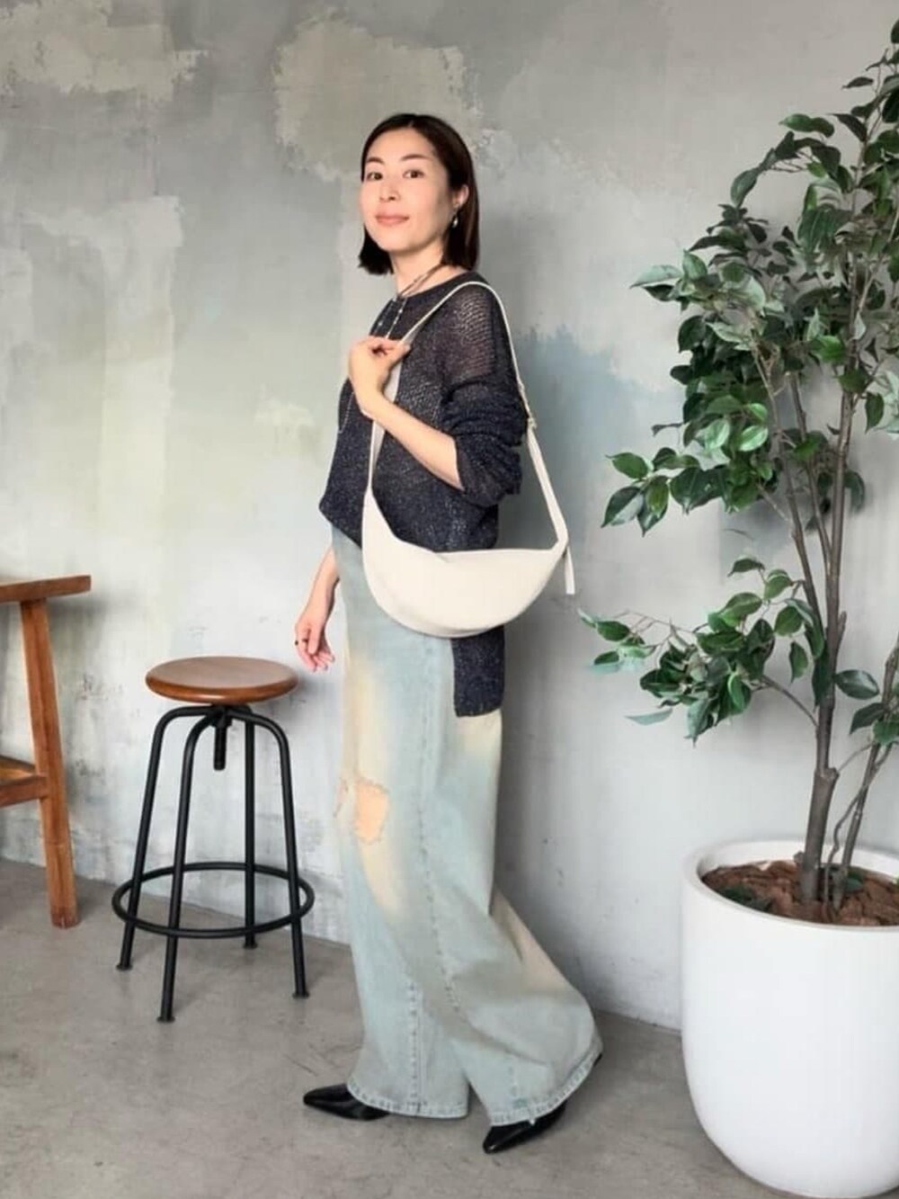 ブルー系のデニムパンツ、ブルー系のニット/セーター、ホワイト系のボディバッグ/ウエストポーチを着用したレディースの夏コーディネートの2枚目の写真