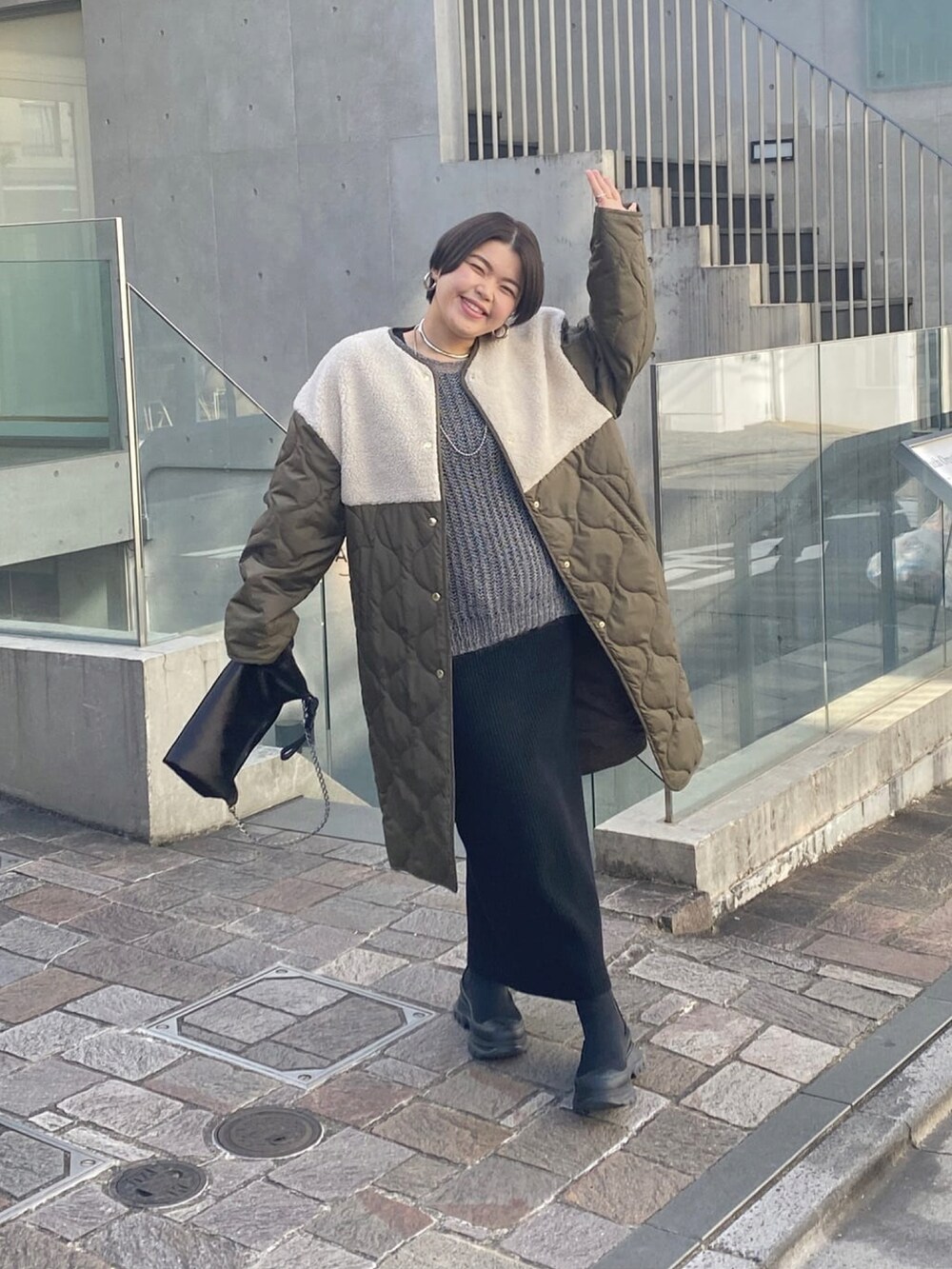 グリーン系のダウンジャケット/コート、グレー系のワンピース、ブラック系のブーツを着用したレディースの冬コーディネートの2枚目の写真