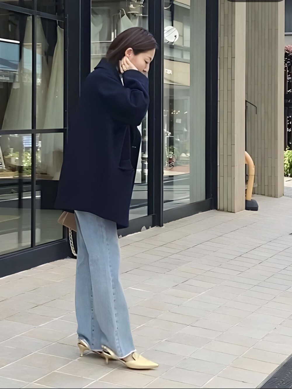 ブルー系のピーコート、ブルー系のデニムパンツ、ゴールド系のパンプスを着用したレディースの冬コーディネートの2枚目の写真